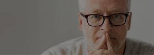 A man with glasses is sitting down