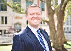 A man in a suit and tie standing next to a tree.