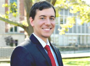 A man in suit and tie standing outside.