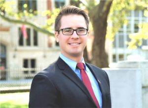 A man in suit and tie standing outside.
