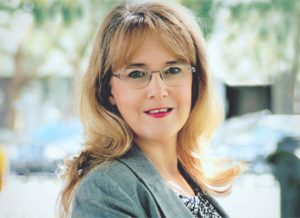 A woman with glasses and long hair wearing a jacket.