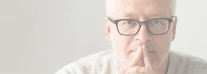 A man with glasses is sitting down
