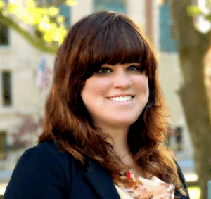 A woman with brown hair and bangs smiles for the camera.