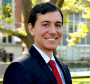 A man in suit and tie standing outside.