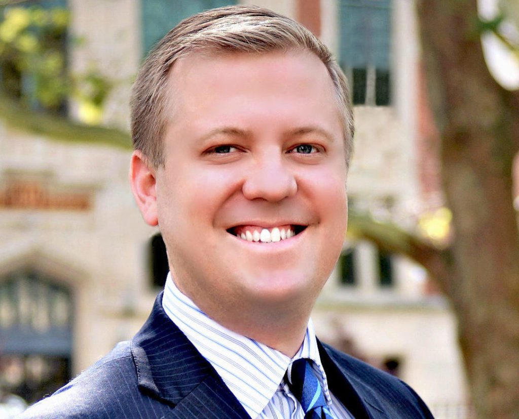 A man in suit and tie smiling for the camera.