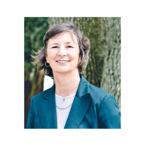 A woman in a green jacket standing next to trees.