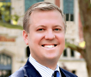 A man in suit and tie smiling for the camera.