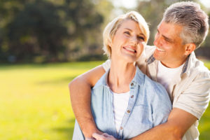 A man and woman hugging in the grass.