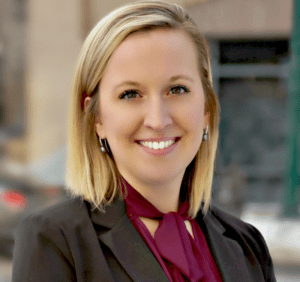 A woman in a suit and tie smiling for the camera.