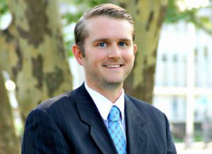 A man in suit and tie smiling for the camera.