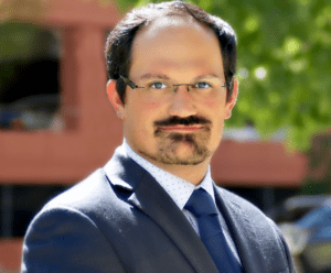 A man in a suit and tie with glasses.