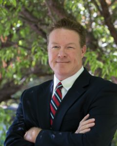 A man in suit and tie with his arms crossed.