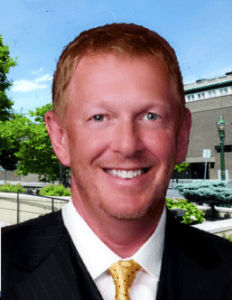 A man in suit and tie smiling for the camera.