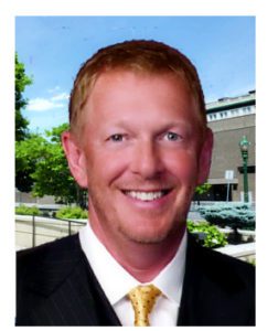 A man in suit and tie smiling for the camera.