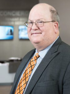 A man in suit and tie standing next to a wall.