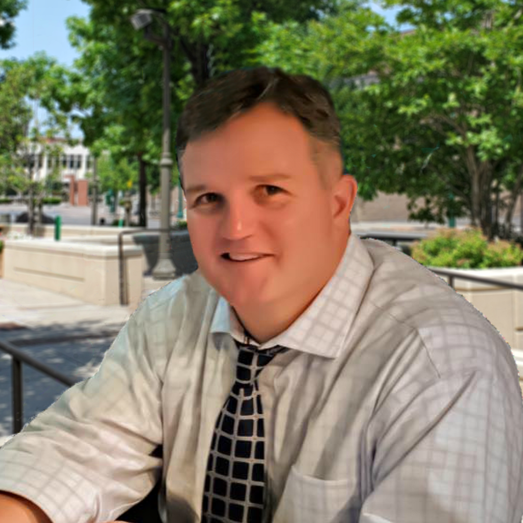 A man in a shirt and tie sitting outside.