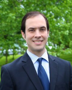 A man in suit and tie standing outside.