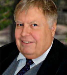 A man in suit and tie smiling for the camera.