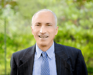 A man in a suit and tie smiling for the camera.