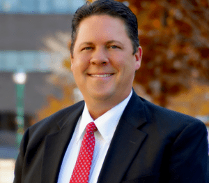 A man in suit and tie smiling for the camera.