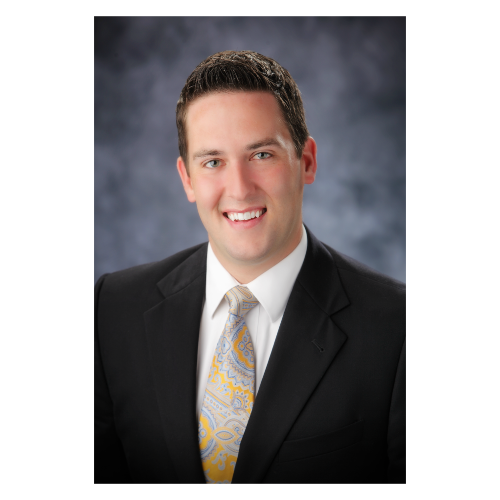 A man in a suit and tie smiling for the camera.