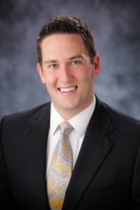 A man in suit and tie smiling for the camera.