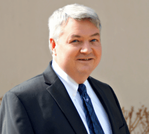 A man in suit and tie standing outside.